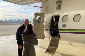 A man standing next to the open door of a plane and talking to a woman.