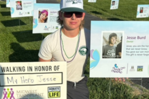 Tyler Barker, Liver Recipient with a picture from Legacy Walk with his Donor Hero Jesse Burd.