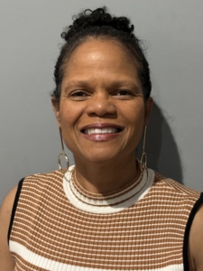 A smiling woman, hair pulled into a top-knot.