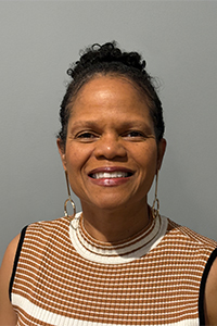 Headshot of Midge Dempsey, smiling, wearing an orange and white striped sleeveless top
