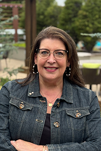 Headshot of Sarah Oland, smiling, wearing a denim jacket