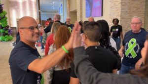 A man gives high fives to people in line at an event.